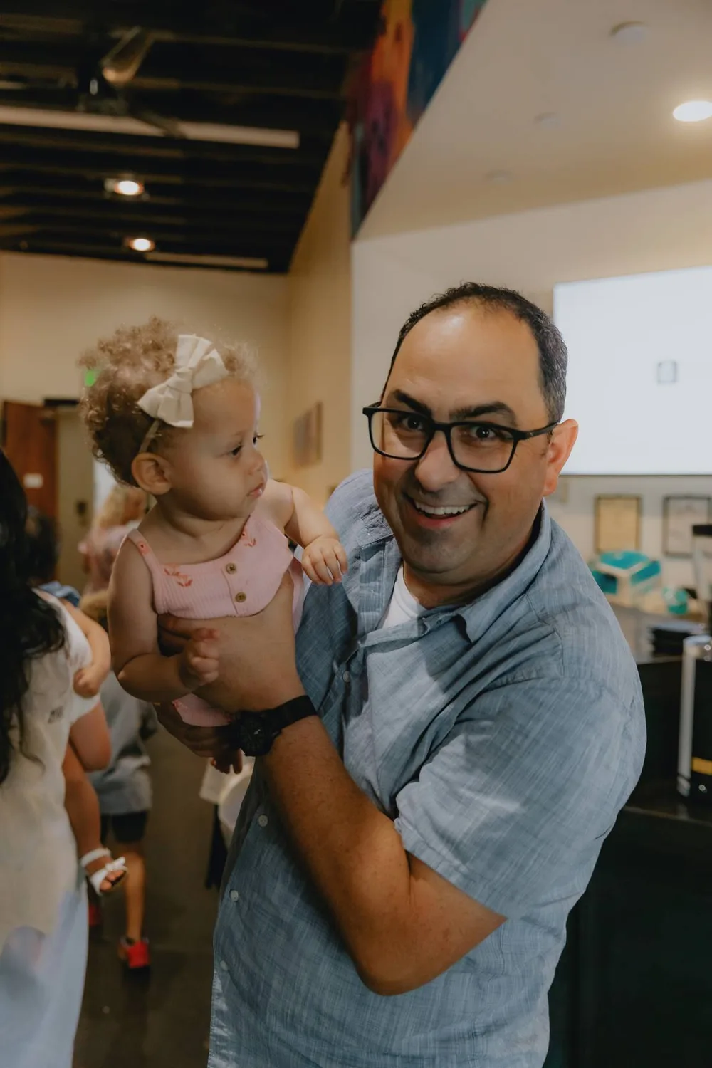 A man smiling and holding a young child at a Sacramento Tabernacle gathering